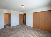 Thumbnail 13 of 25 - a bedroom of an empty apartment with carpeting and wood doors. Fargo, ND Westview Towers Apartments