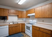 Thumbnail 9 of 25 - an empty kitchen with white appliances and wooden cabinets. Fargo, ND Westview Towers Apartments