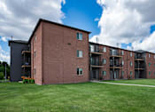 Thumbnail 25 of 25 - a large brick apartment building with a green lawn