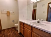Thumbnail 11 of 23 - A bathroom with a sink and a toilet and a mirror. Fargo, ND Flagstone Apartments.