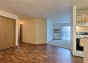 Thumbnail 10 of 23 - an empty living room and kitchen with wood flooring and a door to the bedroom. Fargo, ND Flagstone Apartments