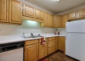 Thumbnail 8 of 23 - A kitchen with white appliances and wooden cabinets. Fargo, ND Flagstone Apartments.