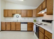 Thumbnail 11 of 18 - an empty kitchen with wooden cabinets and a white counter top. Fargo, ND Flickertail Apartments