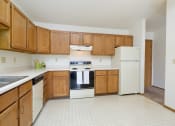 Thumbnail 12 of 18 - an empty kitchen with white appliances and wooden cabinets. Fargo, ND Flickertail Apartments