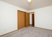 Thumbnail 9 of 18 - a bedroom with a closet and a door to a hallway. Fargo, ND Flickertail Apartments