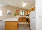 Thumbnail 7 of 18 - a kitchen with a white countertop and wooden cabinets. Fargo, ND Flickertail Apartments