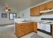 Thumbnail 16 of 18 - an empty kitchen with a sink and stove and a ceiling fan. Fargo, ND Flickertail Apartments