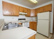 Thumbnail 15 of 18 - a kitchen with white appliances and wooden cabinets. Fargo, ND Flickertail Apartments