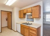 Thumbnail 7 of 15 - a kitchen with a sink and wooden cabinets. Fargo, ND Foxtail Townhomes
