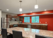 Thumbnail 31 of 32 - a kitchen with a granite counter top island and stainless steel appliances. Fridley, MN Georgetown on the River Apartments