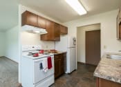 Thumbnail 18 of 34 - a kitchen with white appliances and wooden cabinets and a white refrigerator. Fargo, ND Islander Apartments