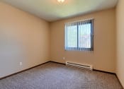 Thumbnail 7 of 12 - a bedroom with carpeted floors and a window. Grand Forks, ND Madison Apartments