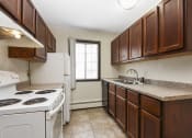 Thumbnail 4 of 32 - Fridley, MN Georgetown Apartments. A kitchen with brown cabinets and white appliances