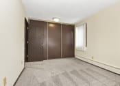 Thumbnail 11 of 32 - Fridley, MN Georgetown Apartments. A bedroom with two doors and a carpeted floor