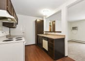 Thumbnail 9 of 32 - Fridley, MN Georgetown Apartments. A kitchen with white appliances and a wooden floor