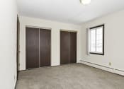 Thumbnail 20 of 32 - an empty room with a window and two closet doors. Fridley, MN Georgetown on the River Apartments
