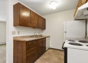 Thumbnail 17 of 32 - an empty kitchen with a stove refrigerator and sink. Fridley, MN Georgetown on the River Apartments