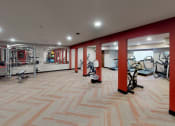 Thumbnail 30 of 32 - a gym with red walls and a wood floor with exercise equipment