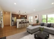 Thumbnail 3 of 29 - Eagan, MN Glen Pond Addition Apartment. A living room with a couch, coffee table, and large window with a kitchen in the background.