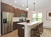Thumbnail 4 of 29 - Eagan, MN Glen Pond Addition Apartments. a kitchen with wooden cabinets and a large island with a white countertop