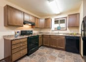 Thumbnail 1 of 10 - a kitchen with brown cabinets and black appliances at Highland Meadows in Bismarck, ND