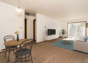 Thumbnail 3 of 16 - Grand Forks, ND Washington Apartments a living room with a table and chairs and a television on the wall