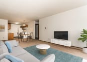 Thumbnail 2 of 16 - Grand Forks, ND Autumn Apartments. a living room with a white couch and a blue rug and a kitchen and diing room in the background.