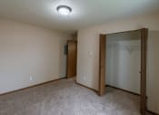 Thumbnail 14 of 16 - Grand Forks, ND Autumn Apartments. A bedroom with carpeted floors and a closet.