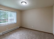 Thumbnail 13 of 16 - Grand Forks, ND Autumn Apartments. A bedroom with carpeted floors and a window.