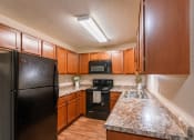 Thumbnail 12 of 16 - Grand Forks, ND Autumn Apartments. A kitchen with black appliances.