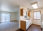 Thumbnail 12 of 16 - an empty kitchen and living room with a refrigerator and a sink. Grand Forks, ND Autumn Ridge Apartments