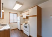 Thumbnail 11 of 16 - a kitchen with white appliances and wooden cabinets and a window. Grand Forks, ND Autumn Ridge Apartments