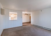 Thumbnail 9 of 16 - a living room with white walls and carpet and a door to a kitchen. Grand Forks, ND Autumn Ridge Apartments