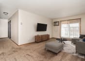 Thumbnail 1 of 7 - Grand Forks, ND Barrette Arms Apartments.  a living room with a couch and a chair and a tv on the wall