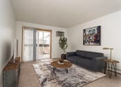 Thumbnail 1 of 19 - Grand Forks, ND Bristol Park Apartments. a living room with white walls and a sliding glass door leading to a balcony
