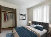 Thumbnail 4 of 11 - Grand Forks, ND Carling Manor Apartments.  a bedroom with a large bed and a closet with a sliding door and a window