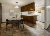 Thumbnail 2 of 11 - Grand Forks, ND Carling Manor Apartments.  a dining area with a table and chairs and a kitchen in the background