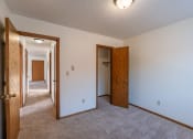 Thumbnail 12 of 14 - a bedroom with a carpeted floor and a hallway with two doors and a closet. Grand Forks, ND Cedarwood Apartments