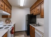 Thumbnail 8 of 14 - a kitchen with white appliances and wooden cabinets and a black refrigerator. Grand Forks, ND Cedarwood Apartments
