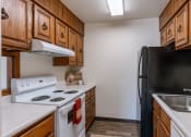 Thumbnail 7 of 14 - a kitchen with white appliances and wooden cabinets and a black refrigerator. Grand Forks, ND Cedarwood Apartments
