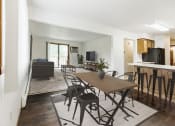 Thumbnail 2 of 11 - Grand Forks, Chandler 1802 Apartments. An dining room with a dining table and chairs and a living room with a couch and tv in the background