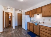 Thumbnail 9 of 19 - a kitchen with wooden cabinets and a white refrigerator and a door. Grand Forks, ND Chandler 1866 Apartments