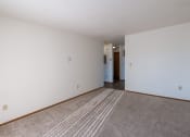 Thumbnail 8 of 19 - an empty living room with carpet and white walls. Grand Forks, ND Chandler 1866 Apartments