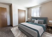 Thumbnail 3 of 19 - Grand Forks, ND Cherry Creek Apartments. A bedroom with a bed and a wardrobe with a window