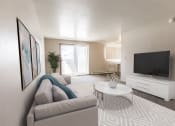 Thumbnail 1 of 19 - Grand Forks, ND Cherry Creek Apartments a living room with a couch and a coffee table in front of a flat screen tv with a sliding glass door in the background