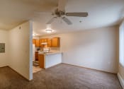 Thumbnail 14 of 17 - Grand Forks, ND Creekside Apartments. An empty living room with a ceiling fan and a kitchen