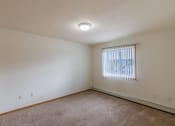 Thumbnail 9 of 17 - Grand Forks, ND Creekside Apartments. A bedroom with carpeted floors and a window.