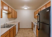 Thumbnail 7 of 17 - Grand Forks, ND Creekside Apartments. A kitchen with a refrigerator and a sink