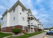 Thumbnail 16 of 17 - Grand Forks, ND Creekside Apartments. A white apartment building with a sidewalk in front of it