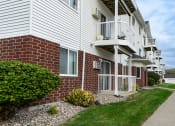 Thumbnail 17 of 17 - Grand Forks, ND Creekside Apartments. A brick and white building with a sidewalk in front of it